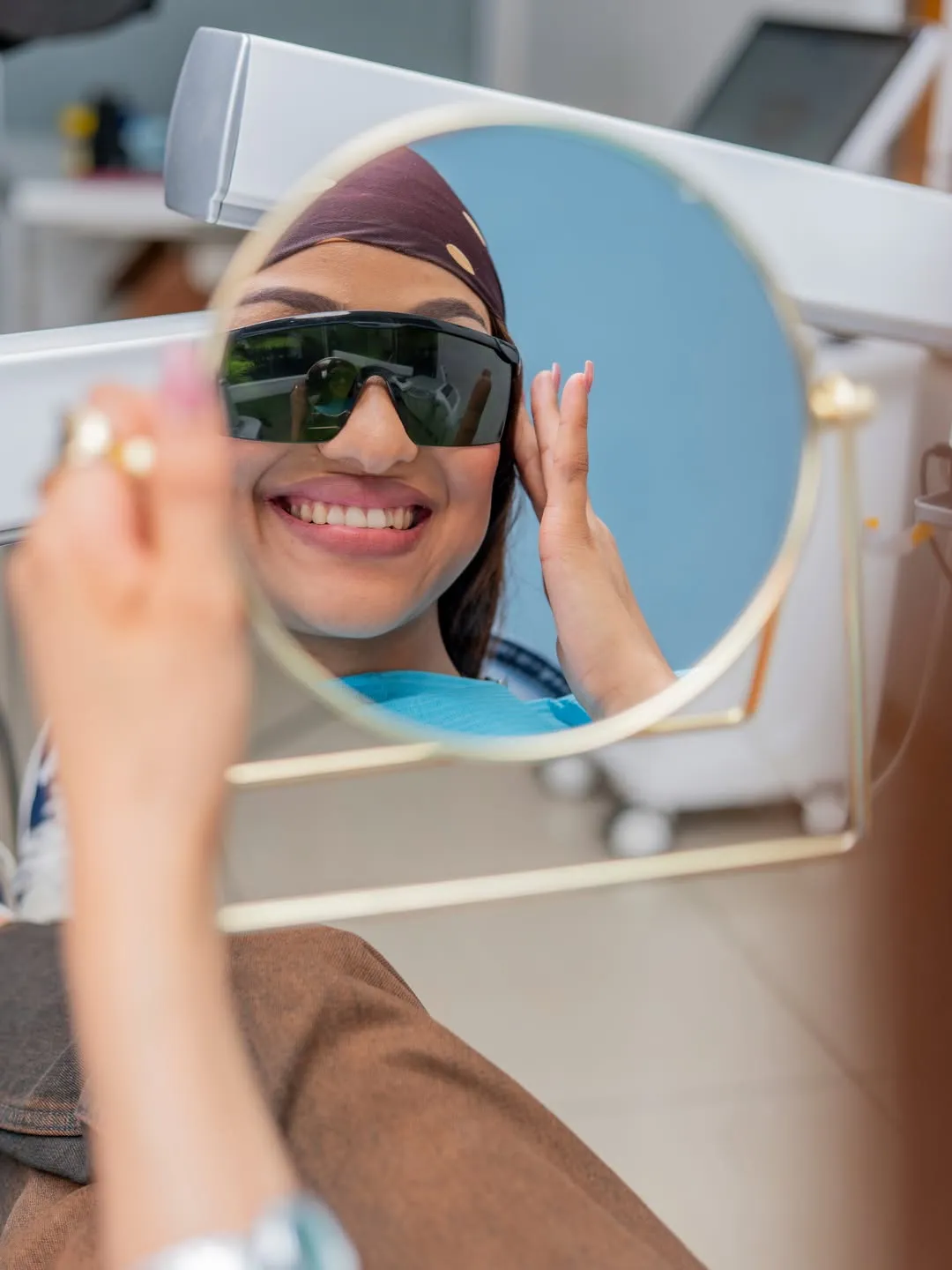 Patient smiling at her reflection after whitening treatment