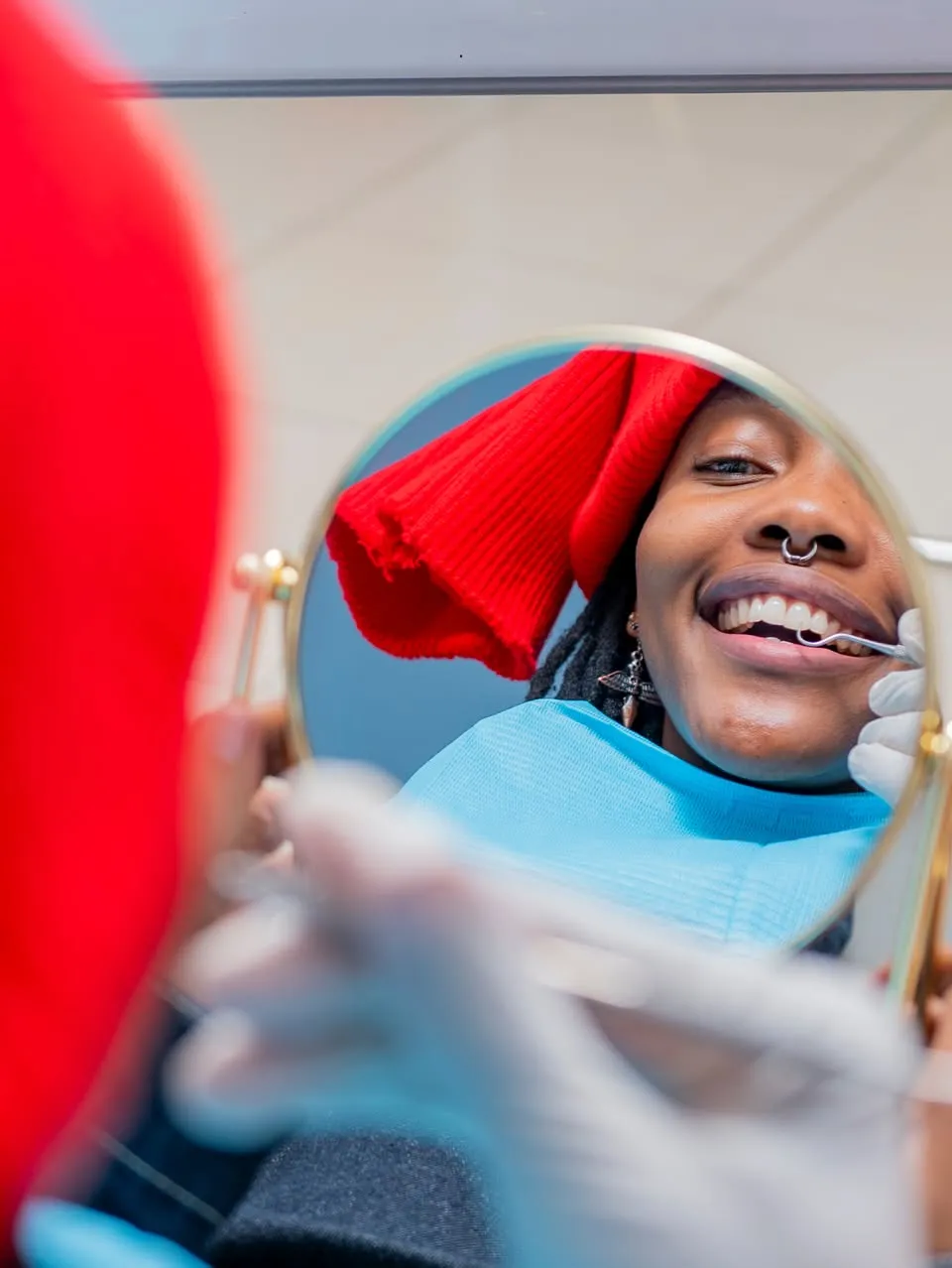 Smiling patient checking her teeth in a hand mirror